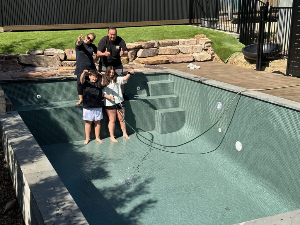 Happy clients in Greensborough filling up completed swimming pool